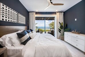 Un dormitorio con una cama grande, un aparador y vista al océano.