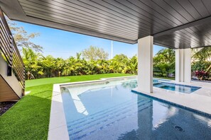 Una piscina moderna al aire libre con vistas despejadas a la exuberante vegetación circundante y un césped cuidado.