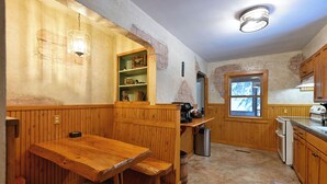 Een landelijke keuken met houten kastjes, een houten tafel en een raam.