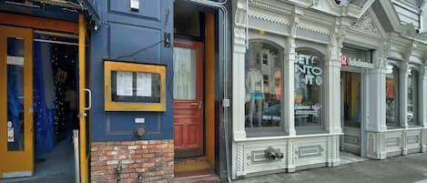 A storefront with a blue awning, a red door, and a window display.