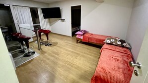 A room with a bed, a TV mounted on the wall, a small table, and a red chair. - Acogedor Departamento en Lima - Jesús María, Ideal Para Familias (Jesús María)