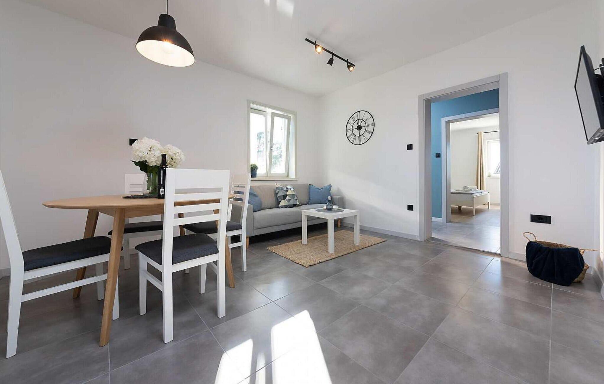 A modern living room with a dining area, a sofa, a coffee table, and a clock on the wall.