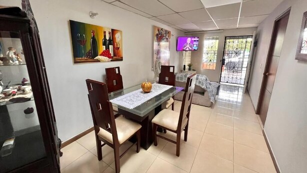 Un coin repas avec une table en verre, des chaises en bois et une citrouille décorative en guise de centre de table.