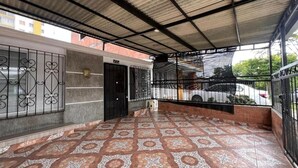 Un espace extérieur abrité doté d’un sol à motifs, d’une clôture en métal et d’une entrée de bâtiment.