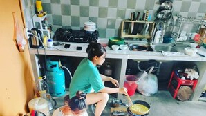 A group of people sitting around a table in a kitchen area with a gas stove and various kitchen utensils. - Buffalo Eco House (Ta Van)