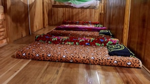 A wooden room with a series of colorful, patterned mats arranged in a row. - Buffalo Eco House (Ta Van)