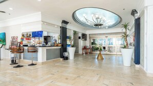 A spacious lobby with a central bar area, large potted plants, and a high ceiling with a skylight. - Lovely  Partial Oceanview Condo at Ocean Manor Resort (Fort Lauderdale)