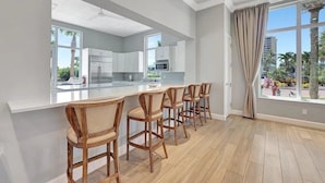 Une cuisine moderne avec des meubles blancs, un îlot central et des tabourets de bar.