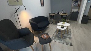 A modern living room with a sofa, armchair, and a small table with a plant. - Hills Nomad Studio (București)