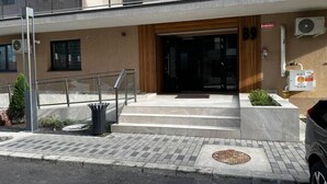 A modern building with a glass entrance, outdoor seating, and air conditioning units. - Hills Nomad Studio (București)