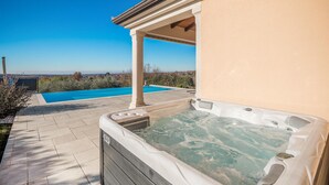 Un jacuzzi con vistas a una piscina y un paisaje lejano.