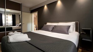 Una habitación de hotel moderna con una cama grande, paredes oscuras y un espejo.