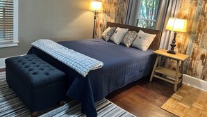 Une chambre à coucher avec un grand lit, deux lampes de chevet, une tête de lit en bois et une fenêtre avec des rideaux.