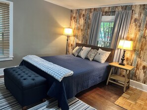 Een slaapkamer met een groot bed, twee bedlampen, een houten hoofdbord en een raam met gordijnen.