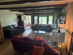 A living room with a sofa, armchair, and a coffee table. There is a door leading outside, and a lamp on a side table. - Beautiful old home with lots of character, a few blocks from downtown Prescott! (Prescott)