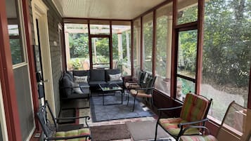 A covered porch with a sofa, chairs, and a table.