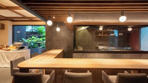Une cuisine moderne avec un plan de travail en bois, des luminaires suspendus et une grande fenêtre donnant sur un jardin.