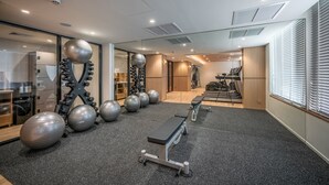 Une salle de sport moderne équipée de matériel d’exercice, d’un long banc et d’un mur recouvert de miroirs.