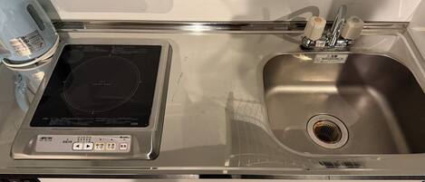 A kitchen with a built-in induction cooktop, a stainless steel sink, and a dishwasher.