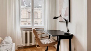 A room with a window, a radiator, a chair, a desk, and a lamp. - Tasteful Margareten 1BR, Fully Furnished & Equipped, by Blueground (Vienna)