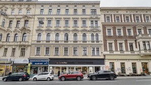 A multi-story building with a row of shops on the ground floor, including a bar. - Tasteful Margareten 1BR, Fully Furnished & Equipped, by Blueground (Vienna)