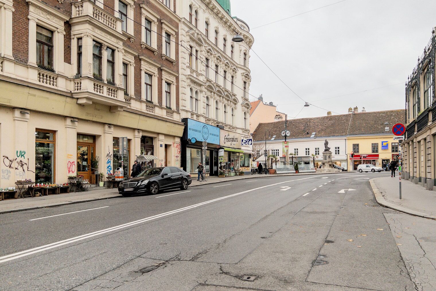 Une rue bordée d’immeubles, une voiture garée et un passage piéton.