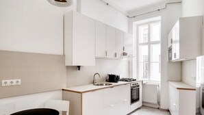 A modern kitchen with white cabinetry, a black countertop, a sink, a stove, and a window providing natural light. - Tasteful Margareten 1BR, Fully Furnished & Equipped, by Blueground (Vienna)