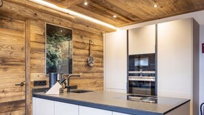 A modern kitchen with wooden paneling, a large island with a sink, and built-in appliances.