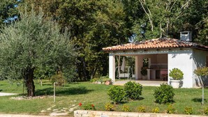 Un petit bâtiment blanc, doté d’un toit en tuiles, entouré de verdure et d’arbres.