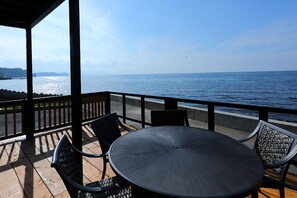 A covered outdoor seating area with a table and chairs, overlooking a body of water. - Otaru Geihinkan (Otaru)