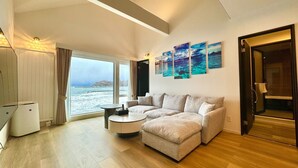 A modern living room with a large window, a sectional sofa, a round coffee table, and artwork on the wall. - Otaru Geihinkan (Otaru)