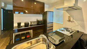 A modern kitchen with dark wooden cabinets, stainless steel appliances, and a black countertop. - Otaru Geihinkan (Otaru)