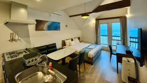 A modern hotel room with a kitchenette, a dining area, a bed with a view of the ocean, and a balcony with a view of the sea. - Otaru Geihinkan (Otaru)