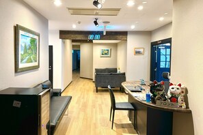 A hotel lobby with a reception desk, a sofa, a bench, and a digital clock displaying 12:25. - Otaru Geihinkan (Otaru)