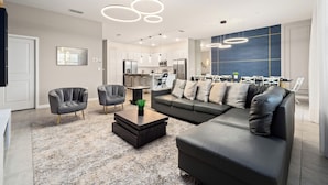 Un salon moderne comprenant un canapé d’angle, deux fauteuils, une table basse et un coin repas avec une table et des chaises.