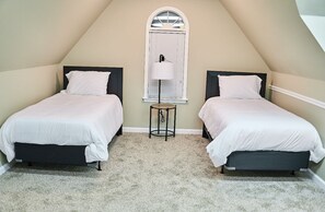Un dormitorio con dos camas, una mesita y una ventana con persianas.