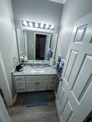 Baño con tocador, lavabo, espejo y área de tocador iluminada.