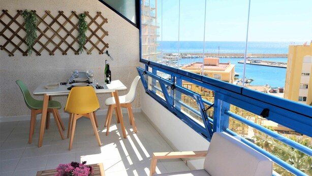 A balcony with a table and chairs, a potted plant, and a view of the sea and buildings. - 37C TB fantastic views (Calp)