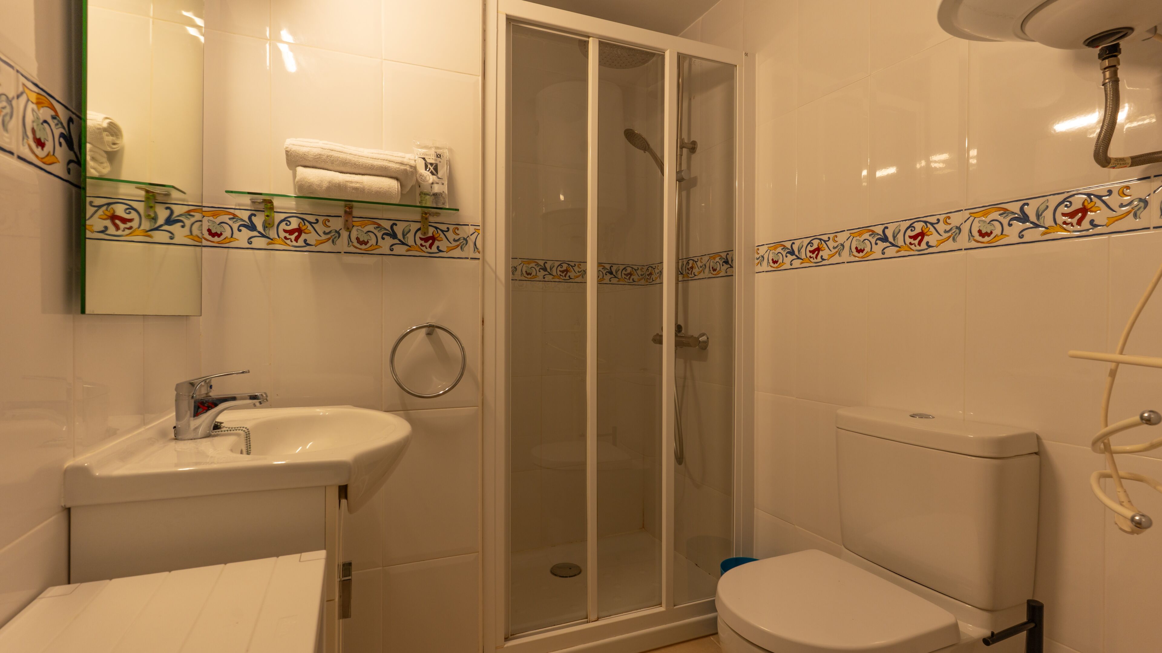 A bathroom with a glass-enclosed shower, a sink, and a toilet.