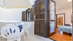 Ein Zimmer mit einem Bett, einem kleinen Tisch mit Stühlen und einer Schiebetür zu einem weiteren Raum.