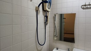 Un baño pequeño con paredes de azulejos blancos, un orinal, un lavamanos y un espejo.