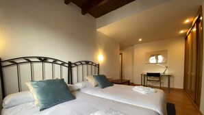 Une chambre d’hôtel avec deux lits, un bureau et une chaise.