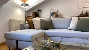 Un salon moderne avec un canapé d’angle, une table basse en verre et des objets décoratifs.