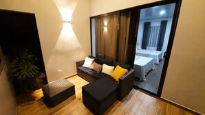 A modern living room with a sofa, ottoman, and a potted plant. - Arenal Monara (La Fortuna)