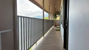 A corridor with a view of a body of water, a potted plant, and a door. - Arenal Monara (La Fortuna)