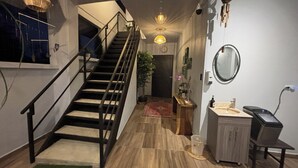 A staircase leading to an upper floor, a small bathroom with a sink and mirror, and a wooden floor. - Arenal Monara (La Fortuna)
