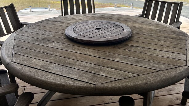 A round wooden table with a central hole, surrounded by four chairs, on a balcony with a view of a coastal landscape. - Karikari Vista (Karikari Peninsula)