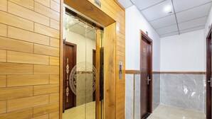 A hallway with wooden walls, a marble floor, and a wooden elevator door. - Saigon Airport Hotel  (Ho Chi Minh City)