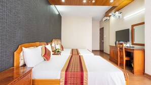 A hotel room with a large bed, wooden headboard, bedside tables, a desk, and a television. - Saigon Airport Hotel  (Ho Chi Minh City)