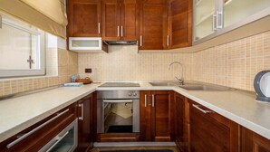 A compact kitchen with wooden cabinets, a stainless steel sink, and a built-in oven. - Cozy home in Porec with WiFi (Porec)